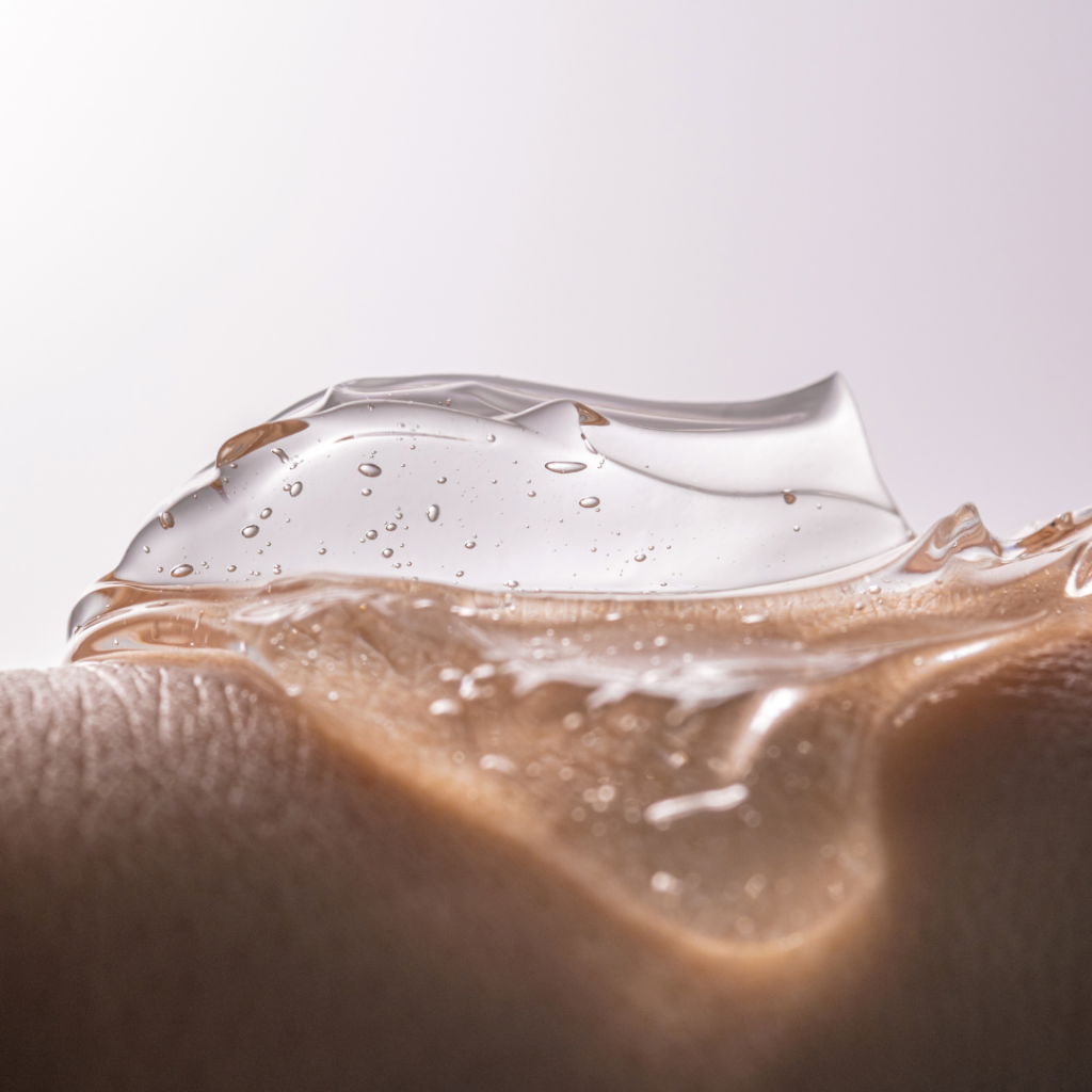 Průhledný hydratační gel kyseliny hyaluronové s bublinkami na lidské kůži, symbolizující plošnou hydrataci pleti.